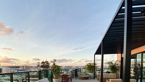 A rooftop terrace with outdoor furniture, including sofas and a coffee table, and a view of the cityscape. - Edificio Liv P.Verde Apto 1108 (Maceió)