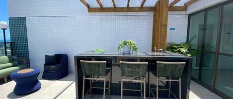 An outdoor patio with a wooden pergola, a black table with chairs, and potted plants.