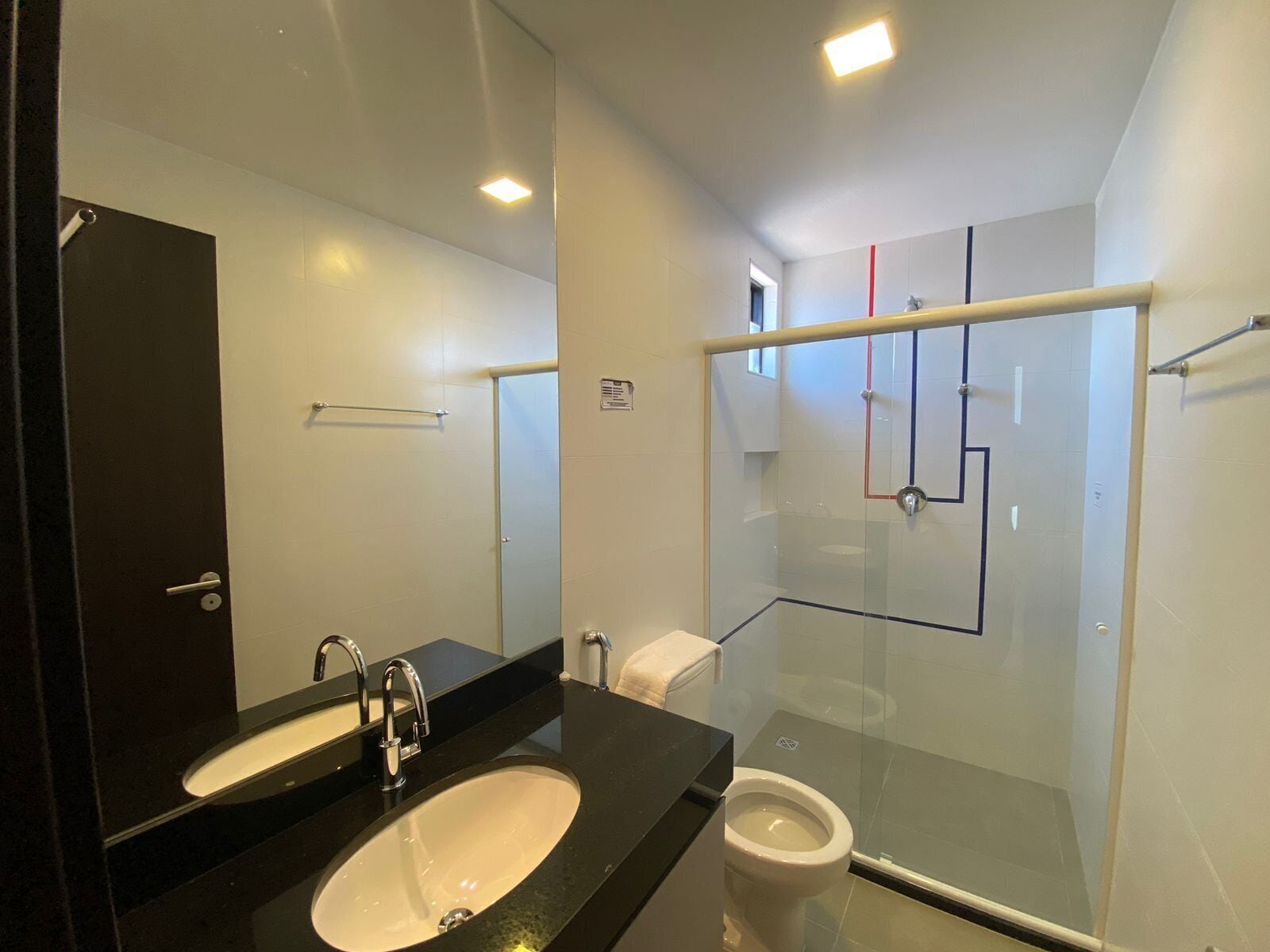 Une salle de bain moderne avec un lavabo noir, des toilettes blanches et une douche à parois de verre.