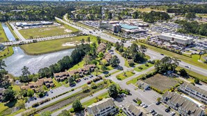 An aerial view of a residential area with a swimming pool, multiple buildings, and a large parking lot. - Cozy Pool side Condo, 5 min from the beach! (Little River)