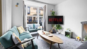 A modern living room with a sofa, coffee table, and a TV displaying "NETFLIX". - Gloster Town House Gorgeous Family Home Barnstaple (Barnstaple)