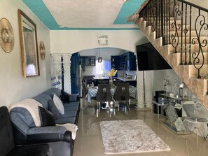 A living room with a sofa, a coffee table, and a staircase leading to a kitchen. - 1 Bedroom Blissful Retreat - A/C & Private Garden (Gravel Hill District)