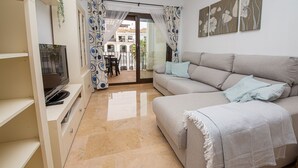 Un salon avec un canapé, un téléviseur et une vue sur le balcon extérieur.