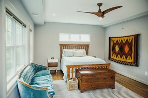 A bedroom with a bed, wooden headboard, bedside tables, a blue sofa, a wooden chest, a ceiling fan, and a large tapestry on the wall. -  6 Bedroom DC Family RetreatRare size in the city!  (Washington)