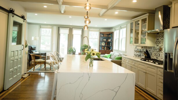 A spacious kitchen with a marble island, modern appliances, and a dining area with a sofa and chairs.