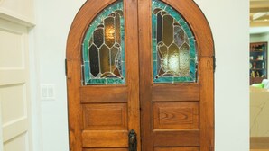 A wooden double door with stained glass windows.