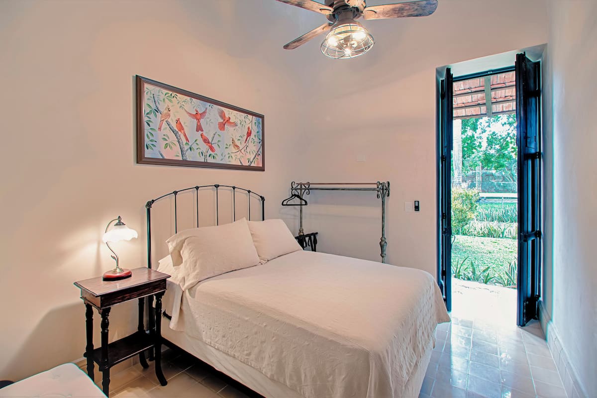 A bedroom with a bed, a nightstand, a ceiling fan, and a window.