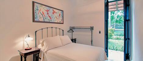 A bedroom with a bed, a nightstand, a ceiling fan, and a window.