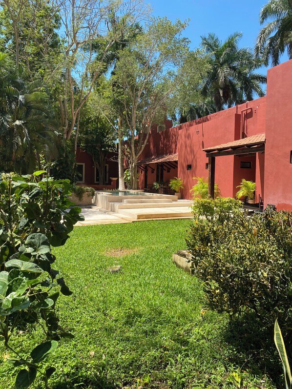 A courtyard with a red building, green grass, and trees.