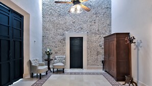 Un couloir avec un tapis à motifs, un ventilateur de plafond, une porte noire et un meuble en bois.