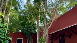 Une piscine entourée d’arbres, avec un bâtiment rouge en arrière-plan.
