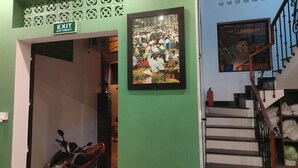 A hallway with an exit sign, a framed photograph, a staircase, and a parked motorcycle. - Nineties Homestay  (Hue)