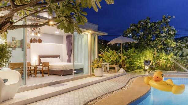 Une chambre d’hôtel moderne dotée d’une porte en verre, d’un lit, d’un bureau et offrant une vue sur l’espace piscine.