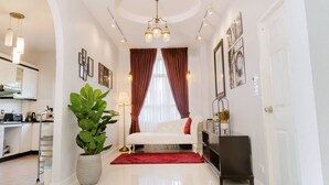 Un salon moderne avec un canapé blanc, des rideaux rouges, une plante en pot et un lustre.