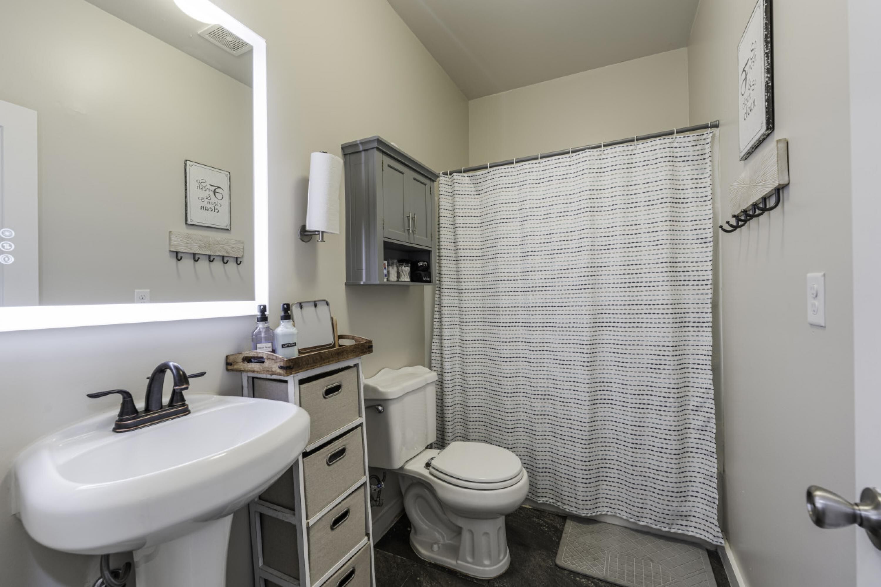 A bathroom with a white sink, a toilet, a shower curtain, and a mirror.