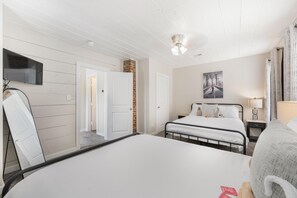Een hotelkamer met een bed, een televisie, een lamp en een schilderij aan de muur.