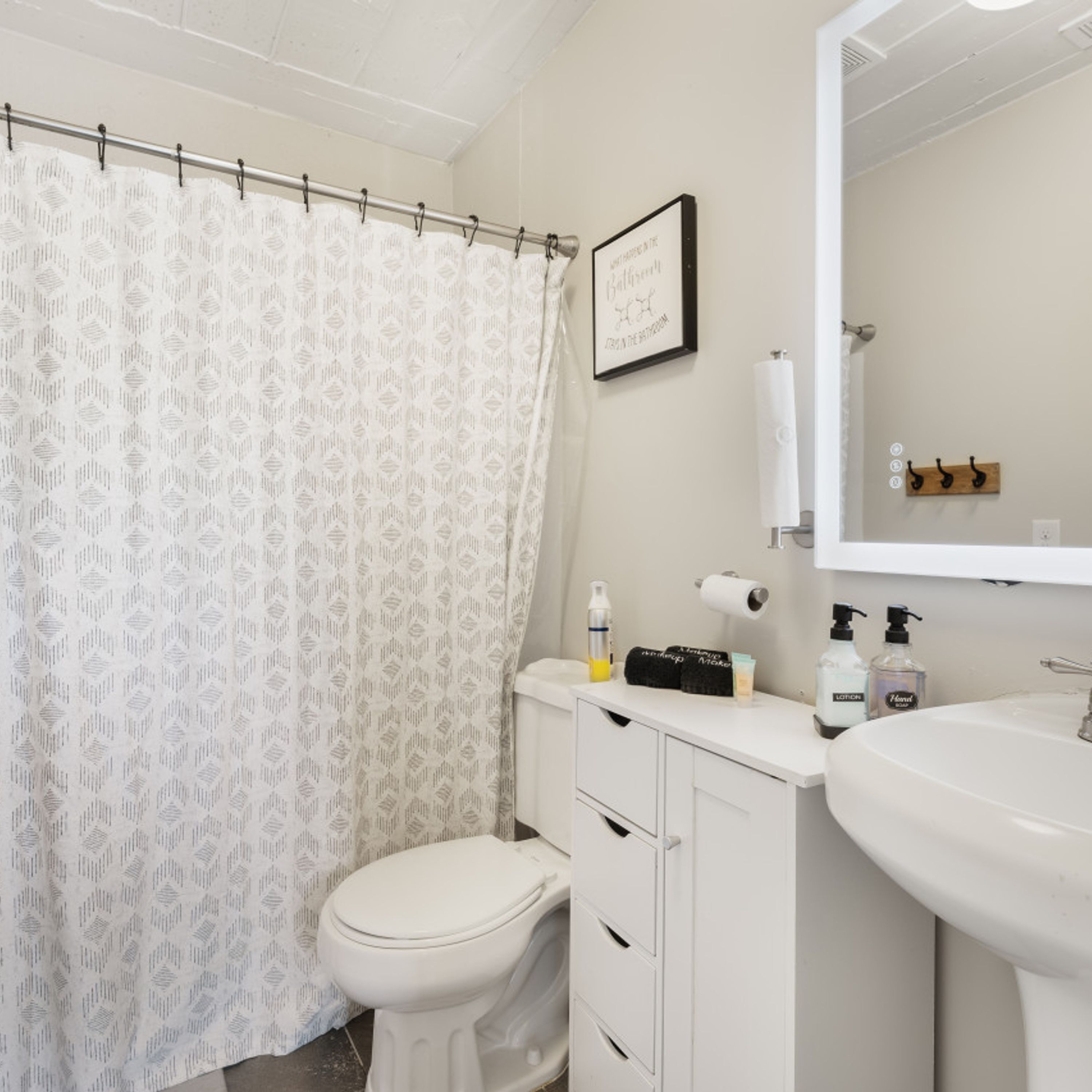A bathroom with a white toilet, a sink, a mirror, and a shower curtain.