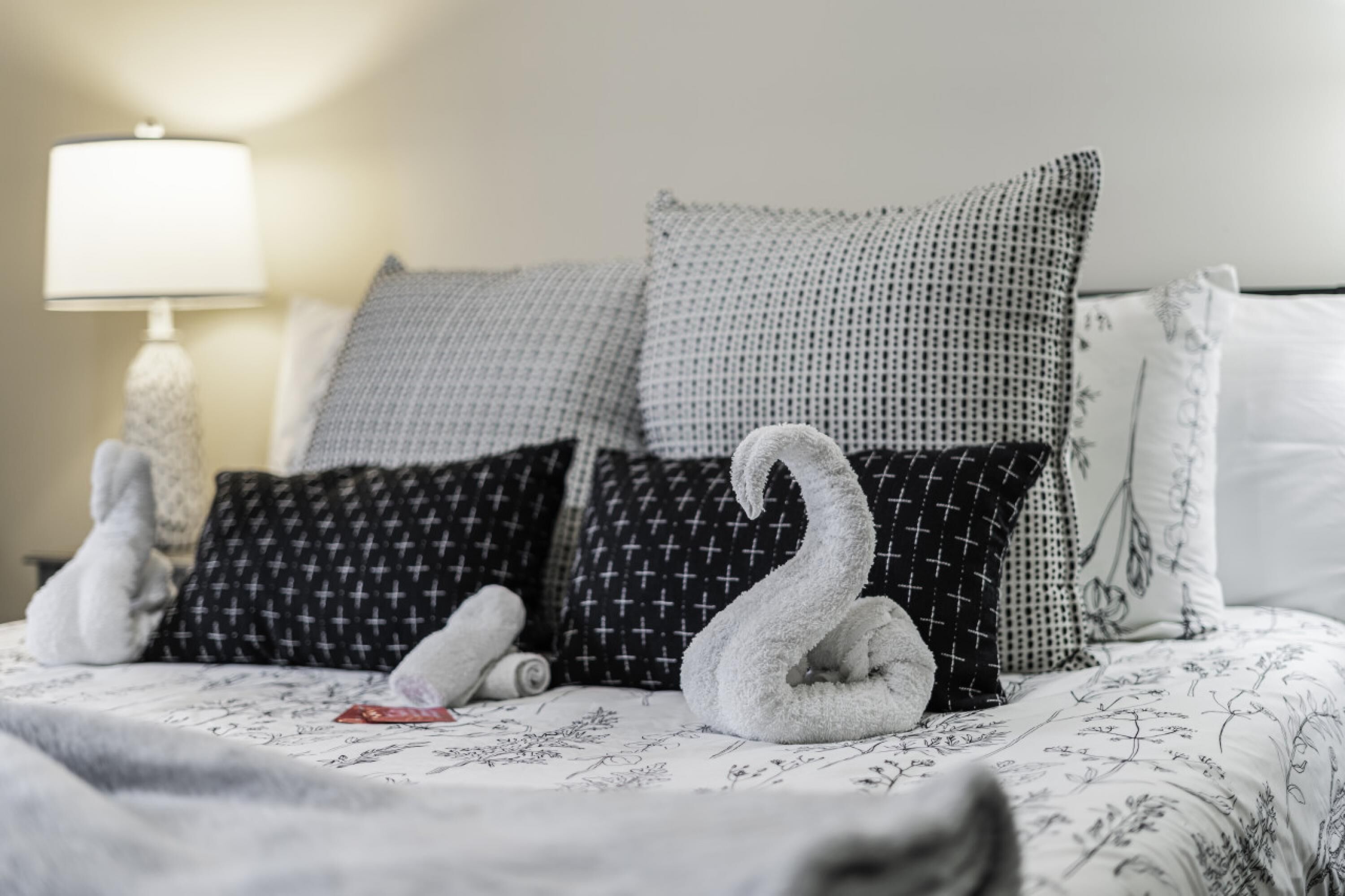 Un letto rifatto con cuscini decorati e un asciugamano a forma di cigno.