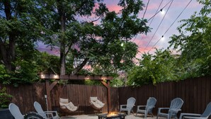 Un jardin avec un foyer, des sièges d’extérieur et une pergola.