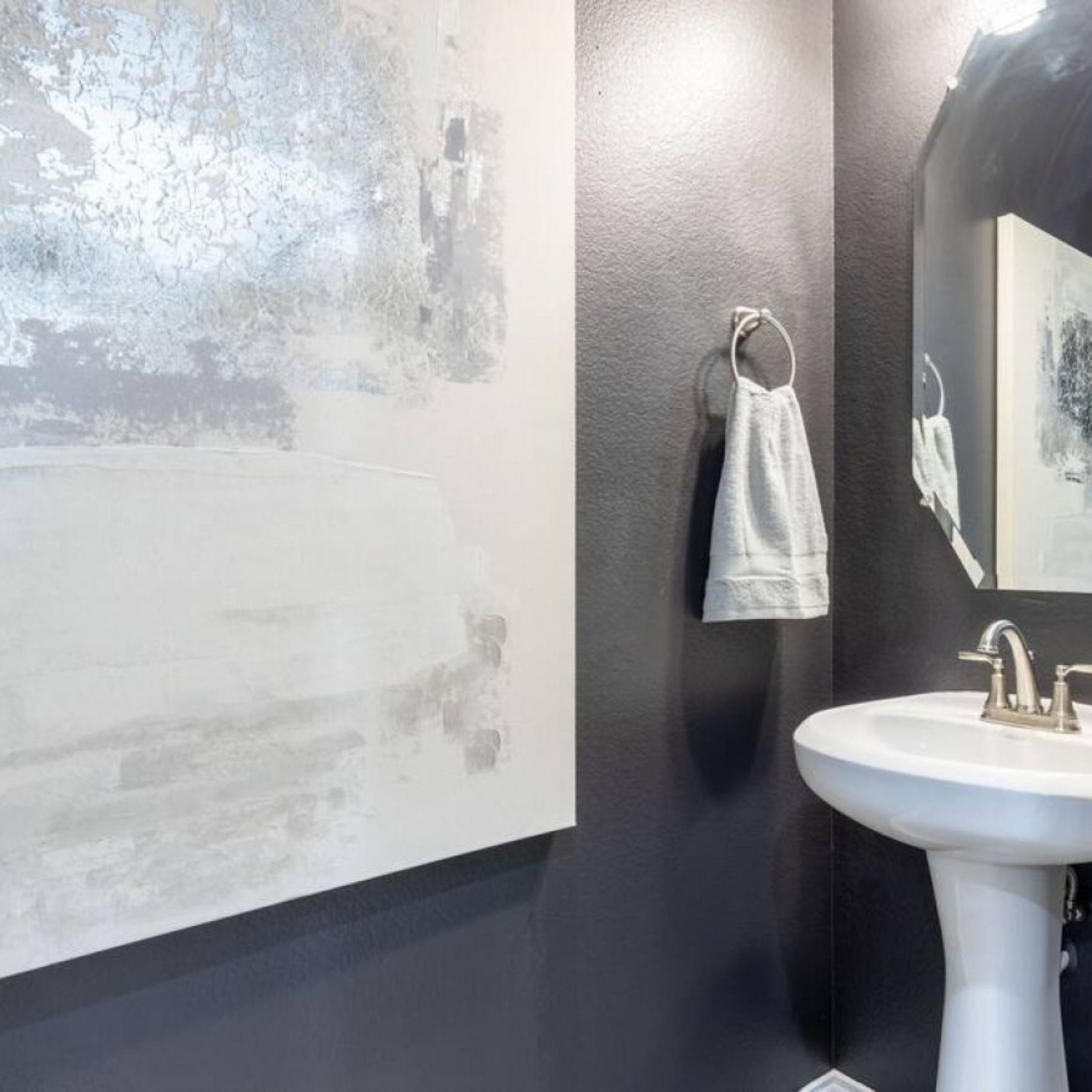 A bathroom with a white sink, a towel hanging on a rack, and a textured wall.
