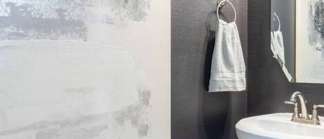 A bathroom with a white sink, a towel hanging on a rack, and a textured wall.