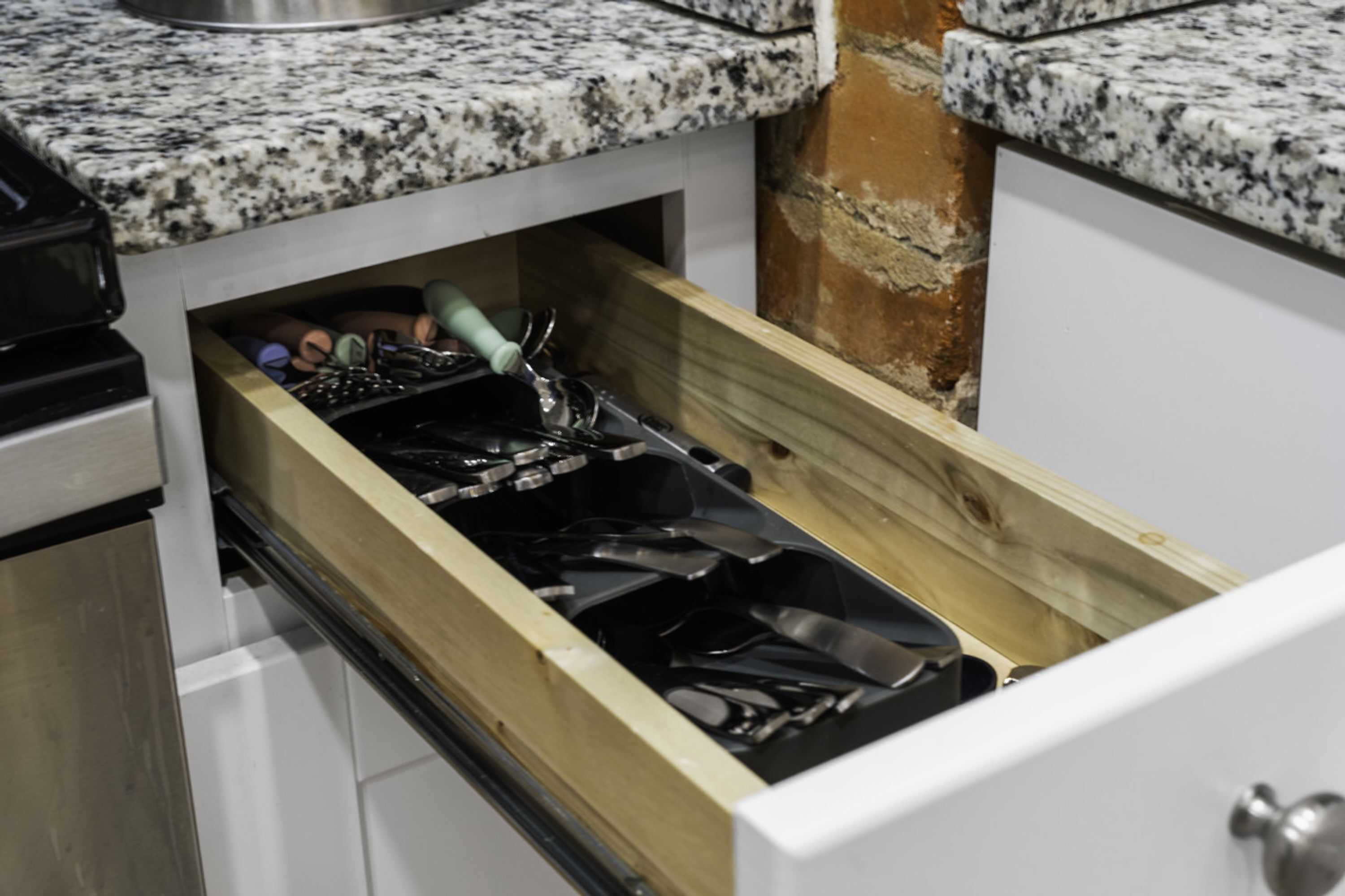 Una cocina con un cajón que contiene varios utensilios y utensilios de cocina.