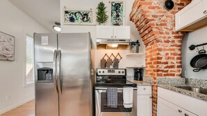 Une cuisine équipée d’un réfrigérateur en acier inoxydable, d’un four et d’un mur en briques.