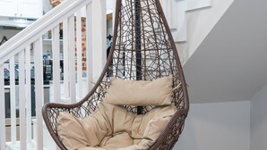 Un fauteuil suspendu avec un coussin beige, dans un intérieur moderne.