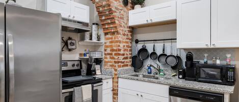 Una cocina moderna con armarios blancos, electrodomésticos de acero inoxidable y un horno de ladrillo.