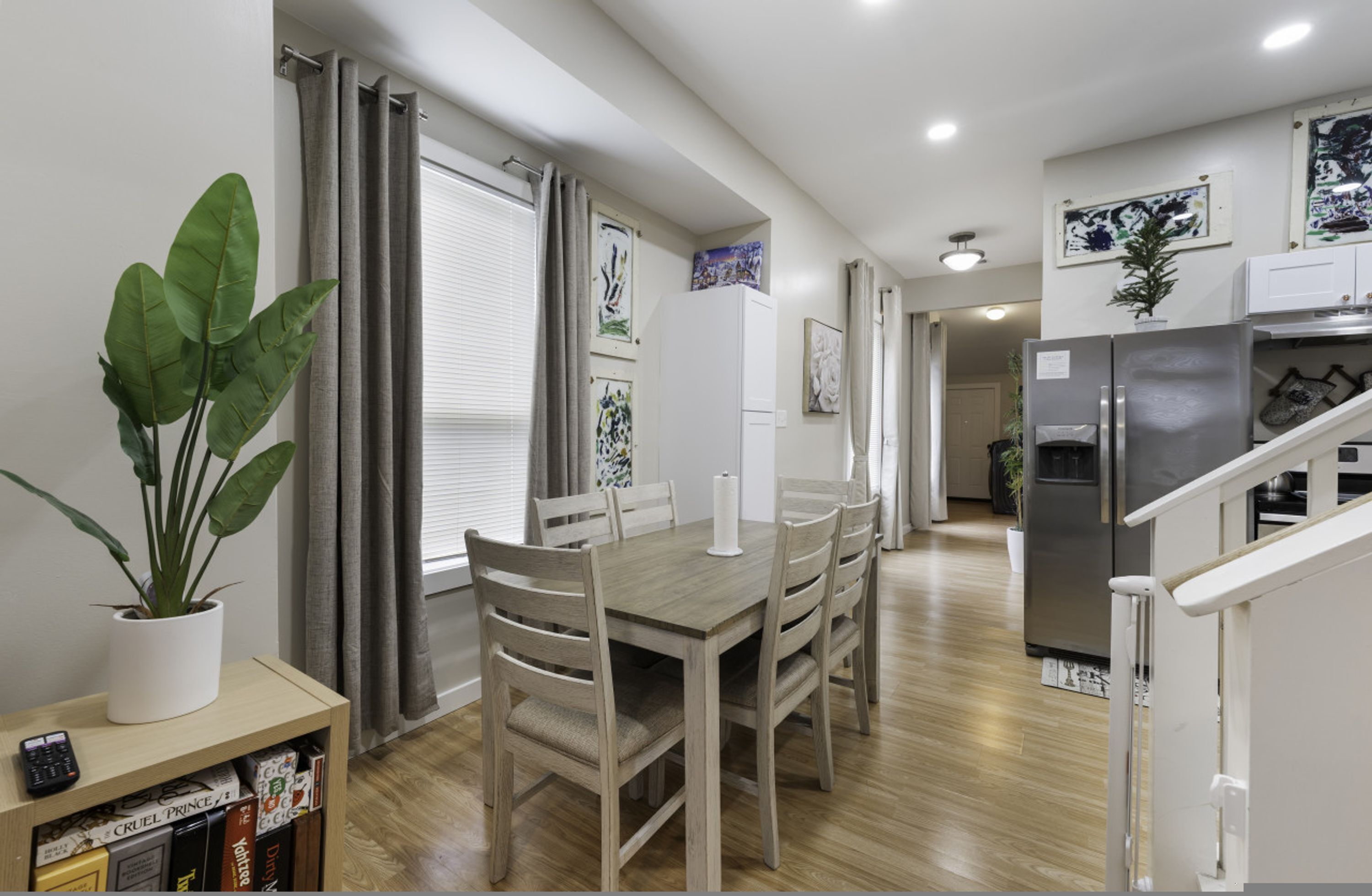 Una cocina moderna con comedor, suelo de madera y una planta en maceta.