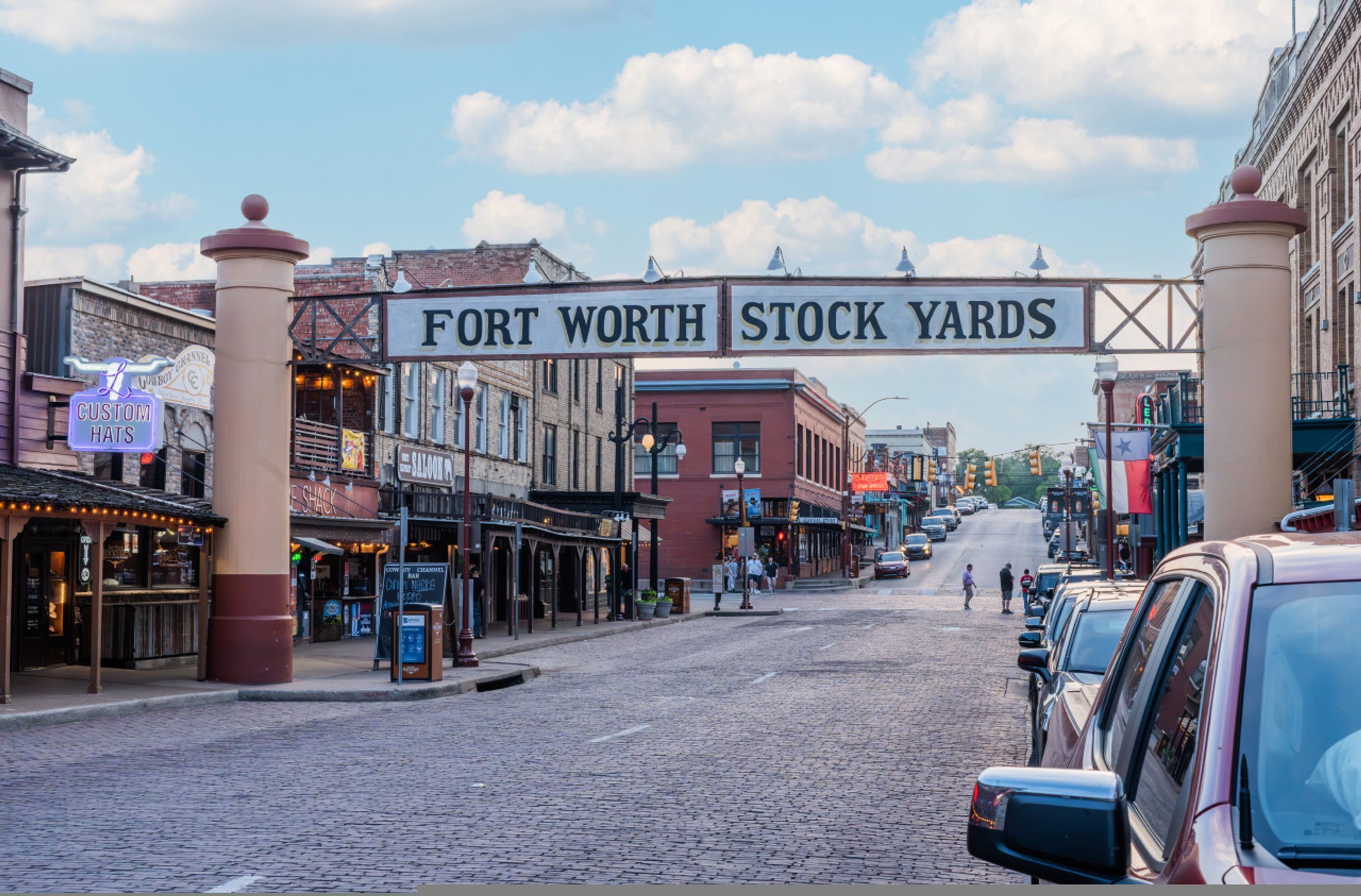 A cobblestone street with a sign reading "FORT WORTH STOCK YARDS".