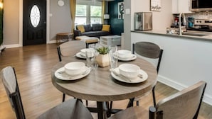A dining area with a round table set for four, a kitchen with modern appliances, and a living room with a sofa and a ceiling fan. - Rare Exclusive Retreat Private Hot Tub King Bed (Arlington)