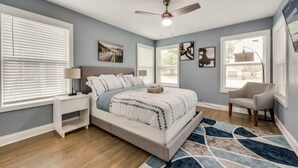 A bedroom with a bed, nightstand, chair, and artwork on the walls. - Rare Exclusive Retreat Private Hot Tub King Bed (Arlington)