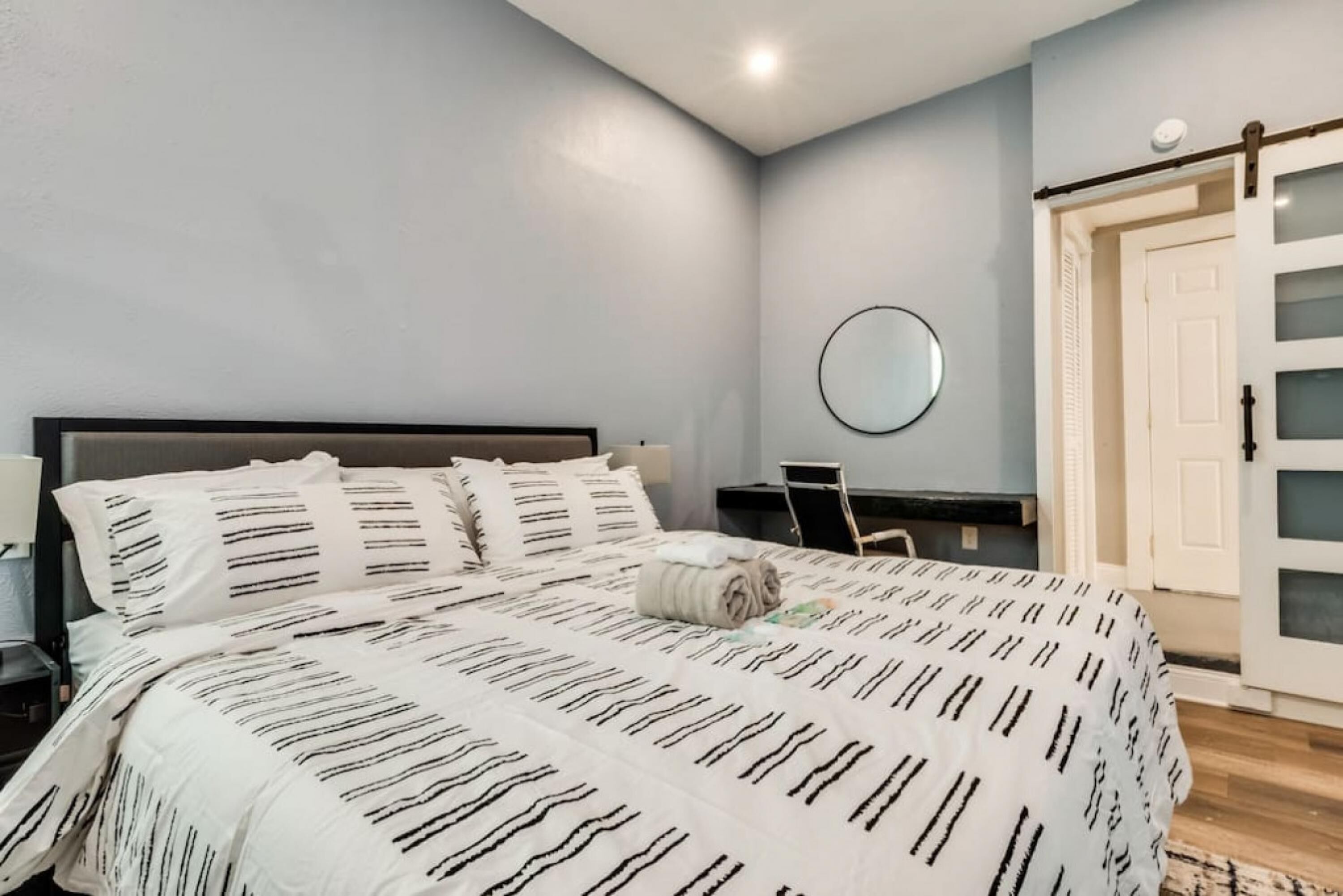 A bedroom with a bed, a desk, and a door.