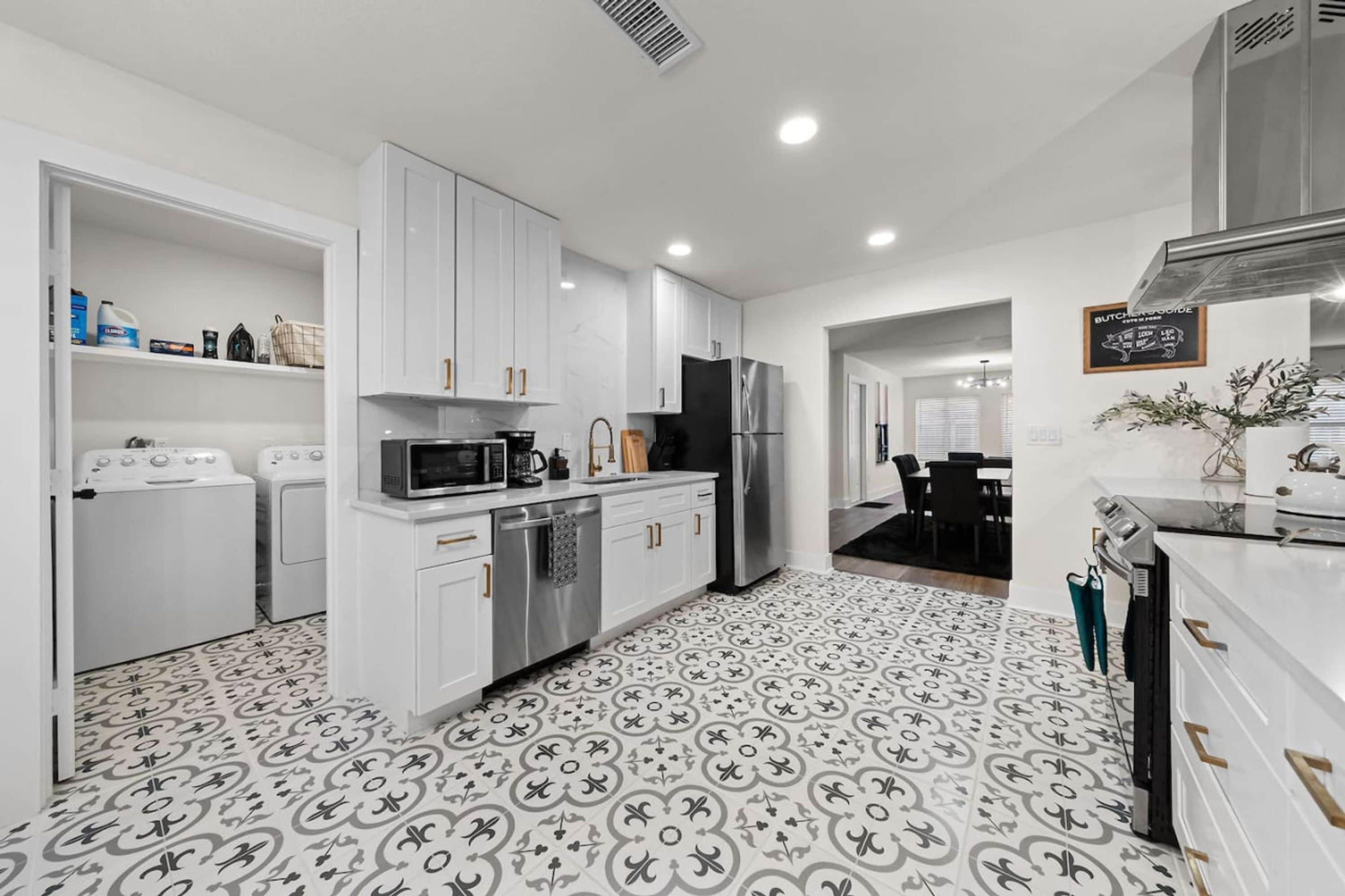 A modern kitchen with white cabinetry, stainless steel appliances, and patterned floor tiles.