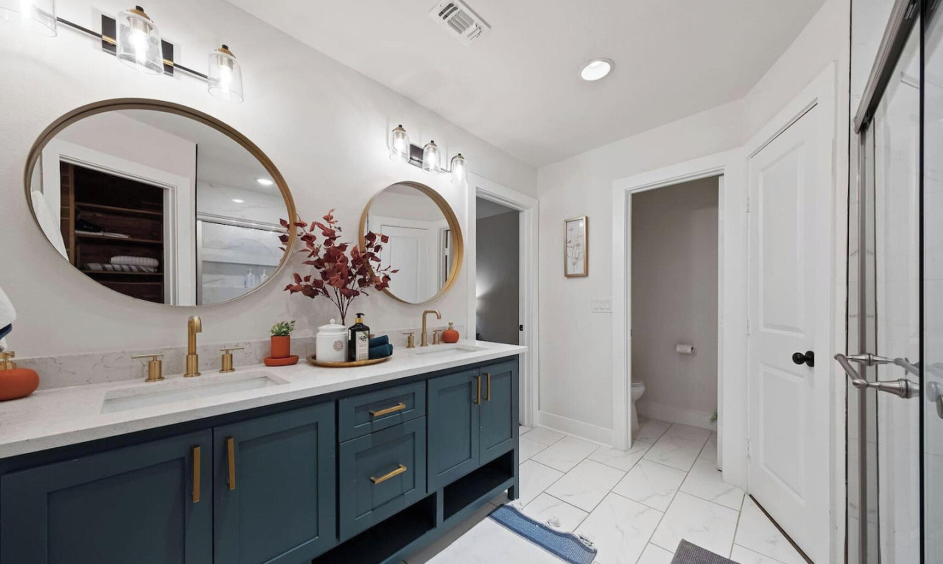 A modern bathroom with a double vanity, large mirrors, and a walk-in shower.