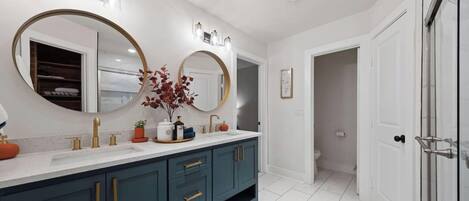 A modern bathroom with a double vanity, large mirrors, and a walk-in shower.