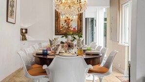 A dining room with a chandelier, white chairs, and a large mirror. - Art Deco Villa Oxford (Oxford)