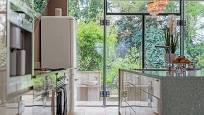 A modern kitchen with a glass door leading to a garden, a built-in oven, and a sink. - Art Deco Villa Oxford (Oxford)