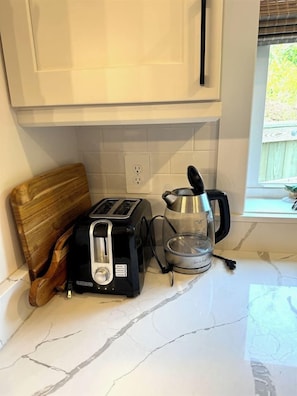 Eine Küchenarbeitsplatte mit einem Toaster, einem Wasserkocher und einem Holzschneidebrett.