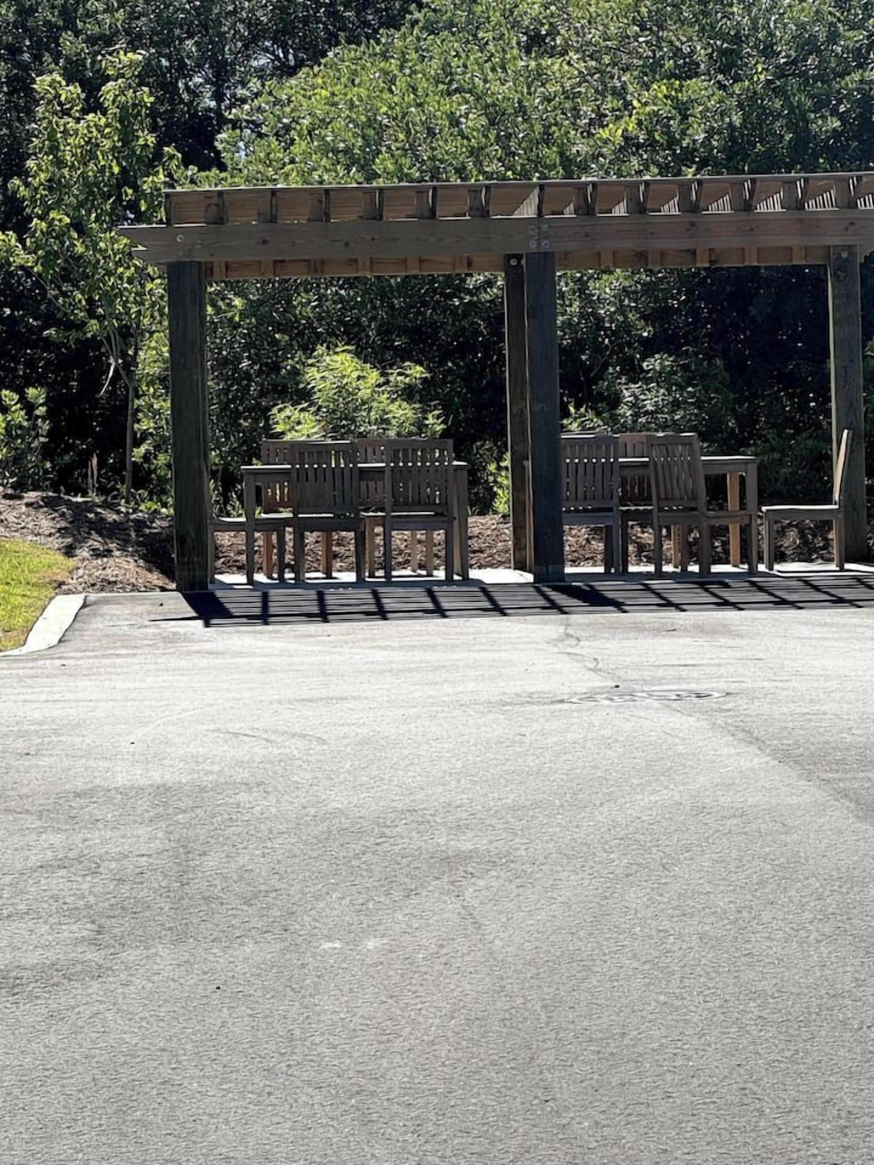 A covered outdoor seating area with benches and a pergola structure.