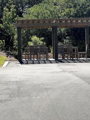 A covered outdoor seating area with benches and a pergola structure.
