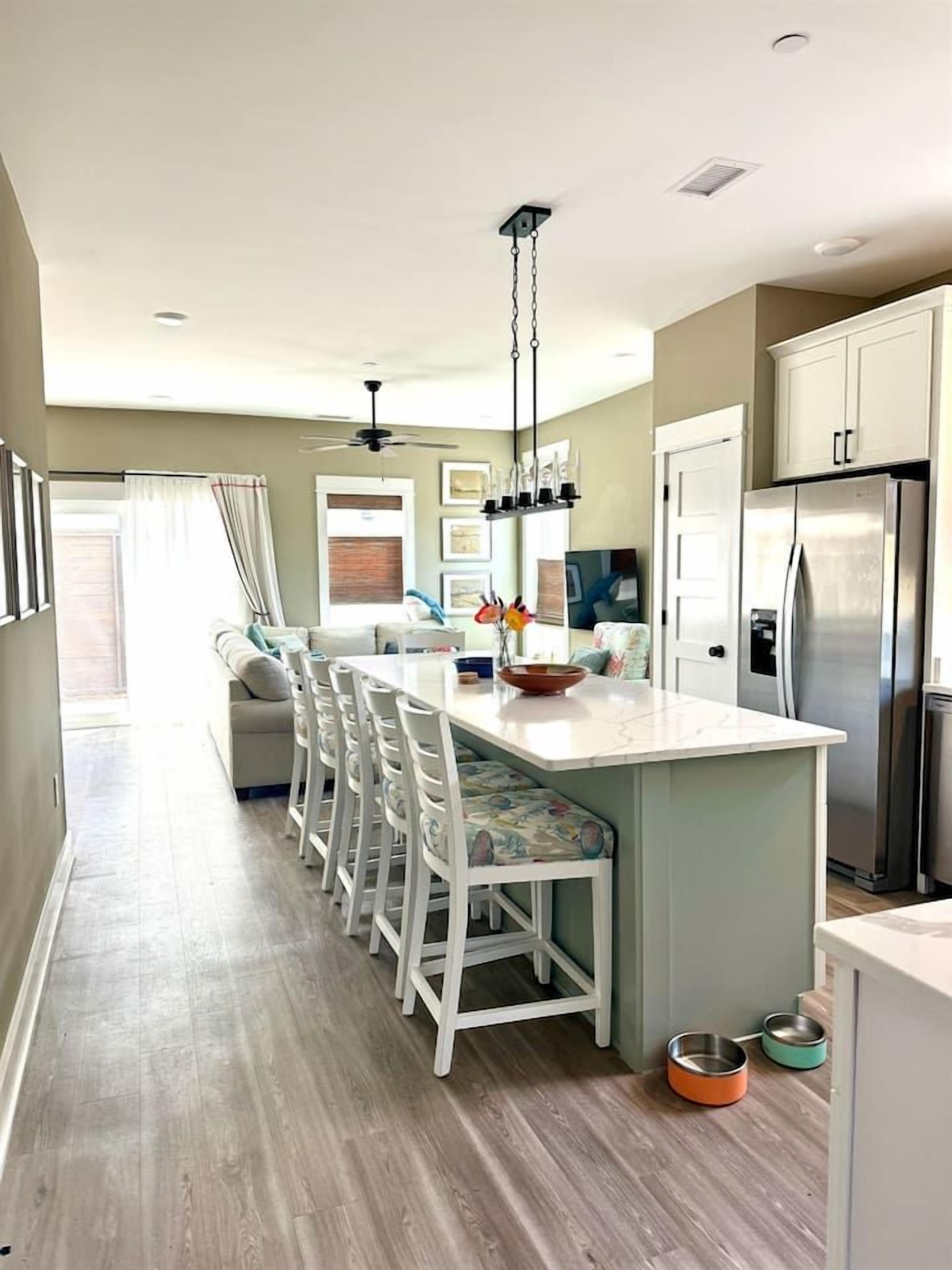 Una cocina moderna con una isla central, armarios blancos y electrodomésticos de acero inoxidable.