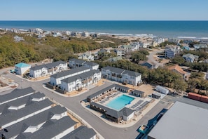 A residential area with a large swimming pool, multiple houses, and a beach in the background. - NEW! Prime Location @Beach Club -Tranquil Seascape (Corolla)