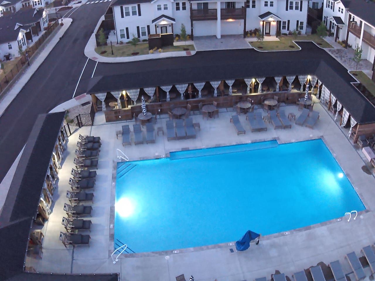 An aerial view of a hotel with a large swimming pool surrounded by lounge chairs and umbrellas.
