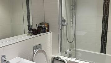 A modern bathroom with a glass shower enclosure, a white toilet, and a sink.