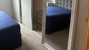 A bedroom with a bed, a wardrobe, and a large mirror. - Inviting 2-bed Apartment in Bushey (Bushey)