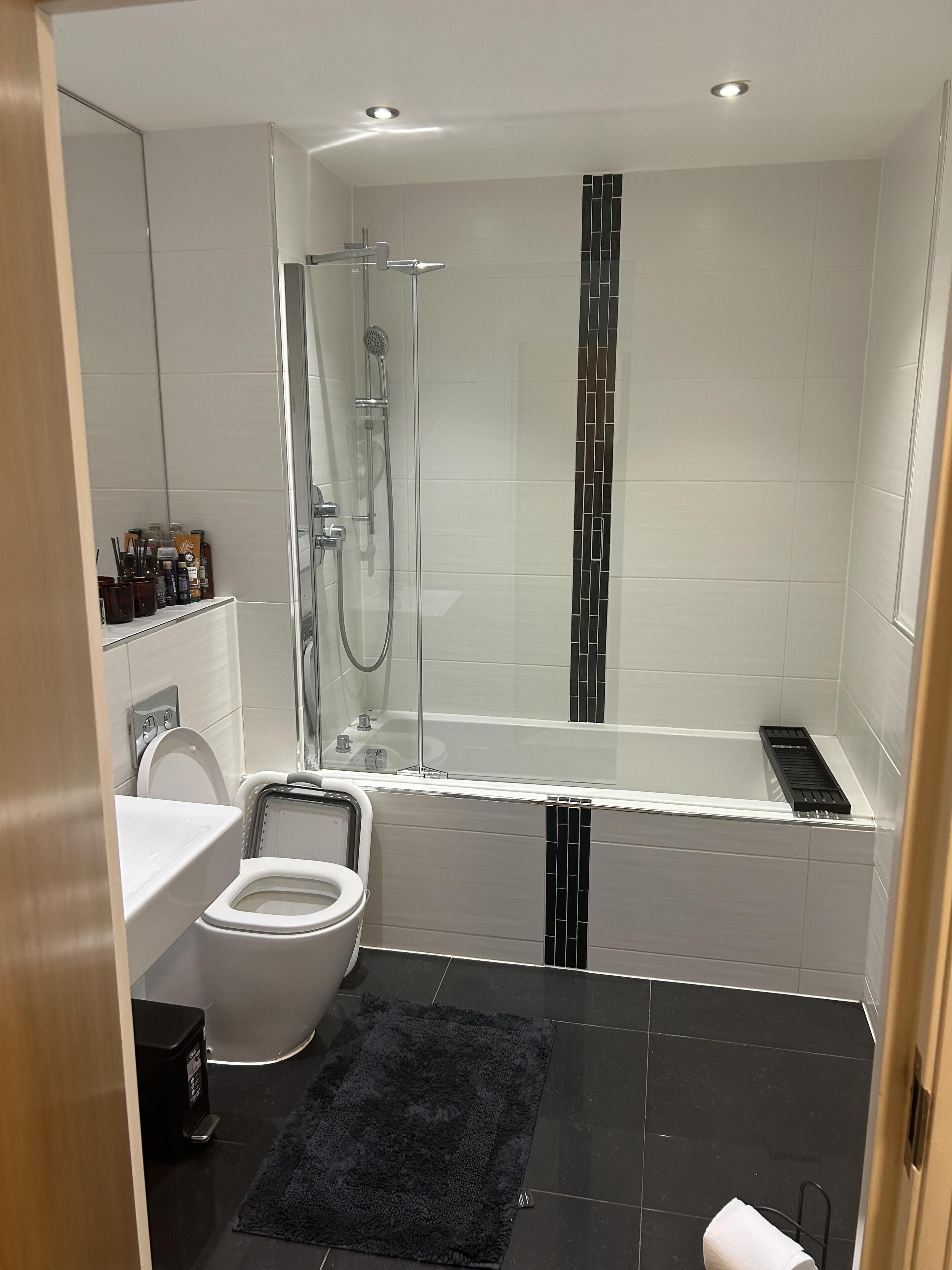 Une salle de bain moderne dotée d’une douche à parois de verre, d’une baignoire, de toilettes et d’un lavabo.