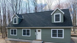 A two-story house with a dark green exterior, white trim, and a grey roof. - Built for You - 4BR w/ Playground, Sauna, Games! (Harbor Springs)