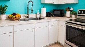 A kitchen with white cabinets, a stainless steel sink, a microwave, and an oven.
